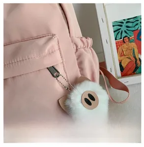 Gros plan d'une peluche de cochon blanc accrochée à la fermeture d'un sac à dos rose