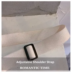 Detail of adjustable off-white woven shoulder strap with black buckle on messenger bag