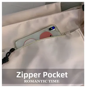 Detail of the outer zipper pocket on beige messenger bag showing smartphone storage