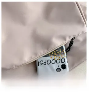 Close-up of a light pink crossbody bag showing a functional front zipper pocket with phone