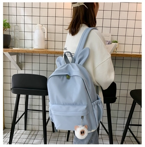 Détail d'un sac à dos en nylon bleu clair avec oreilles de lapin et pompon peluche