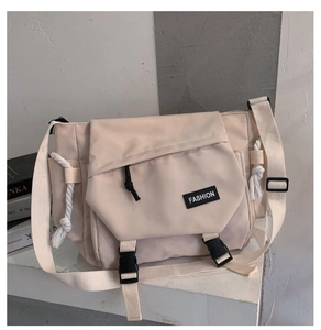 Detail view of cream functional messenger bag with black buckles and fashion logo label