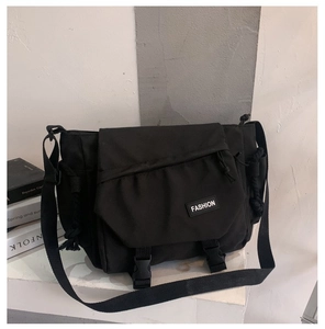 Detail of black canvas messenger bag featuring plastic buckles and adjustable wide strap