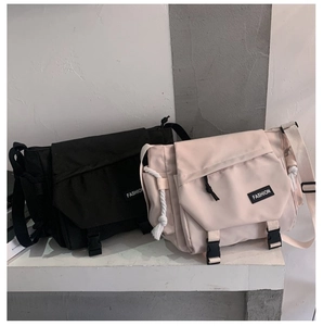 Detail view of large capacity messenger bags in black and beige with buckle closures