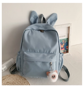 Détail d'un sac à dos bleu ciel pour étudiant avec oreilles de lapin et charme cochon