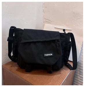 Detail of black utility messenger bag with flap cover and adjustable fabric shoulder strap
