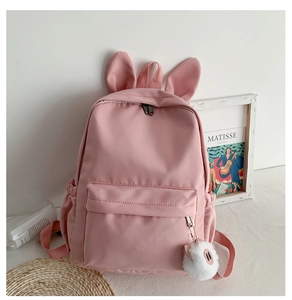Vue détaillée d'un sac à dos rose avec oreilles de lapin et un charme de cochon en peluche