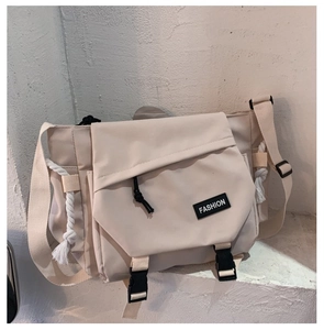Close-up of beige messenger bag with buckle closure and fashion label detail