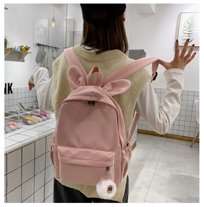 Détail du dos d'un sac à dos rose en nylon avec oreilles de lapin et pompon doux