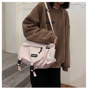 Detail of beige messenger bag with buckle closure and fashion label on shoulder strap