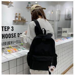 Détail d'un sac à dos noir avec oreilles de lapin mignonnes et porte-clé cochon en peluche