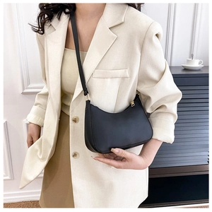 Detail einer minimalistischen schwarzen Hobo-Tasche mit goldenen Beschlägen am Blazer