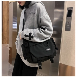 Detail of black utility messenger bag with buckle straps and fashion logo label