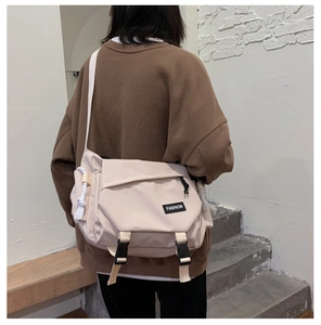 Model view of large cream messenger bag showing functional crossbody fit and buckle detail