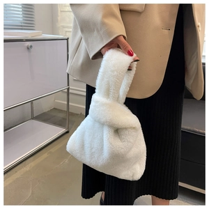Detail of white plush faux fur knot handbag with soft texture and round fluffy shape