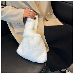 Close-up of white plush knot handbag showing soft faux fur texture and elegant design