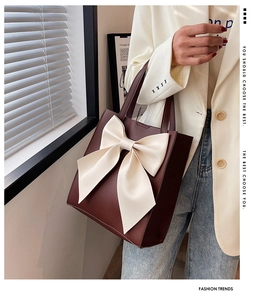 Close-up of deep wine red tote bag with large cream bow detail and sturdy top handle