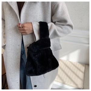 Close-up of black faux fur knot handbag featuring soft microfiber texture and minimalist style