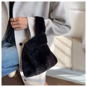 Chic black plush knot bag paired with a wool coat and blue jeans for a stylish winter look
