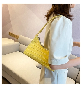 Macro view of bright yellow crocodile embossed leather texture on baguette shoulder bag