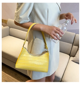 Model wearing a bright yellow crocodile pattern baguette bag in a stylish indoor setting