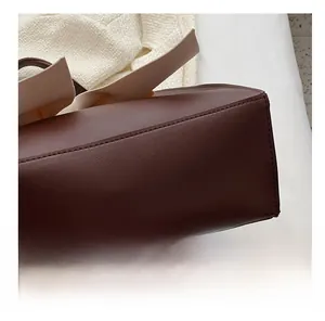 Detailed macro view of the reinforced bottom stitching on a dark brown leather tote bag