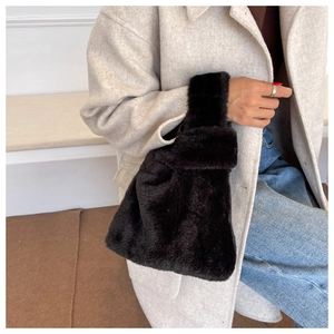 Close-up of black faux fur handbag held by model wearing a stylish winter wool coat