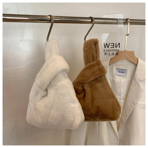 Detailed view of fluffy faux fur wristlet bags in white and camel on display hooks