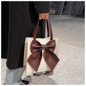Close-up of minimalist beige tote bag with a large contrasting brown bow decoration