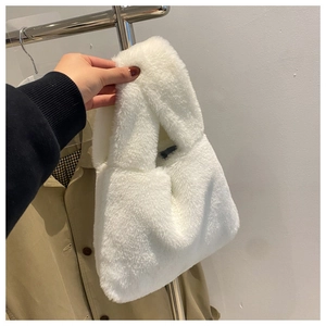 Detail view of white plush handbag featuring soft faux fur texture and top handle
