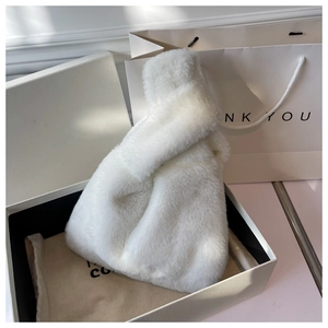 Close-up of fluffy white faux fur handbag with knotted handle in premium gift packaging