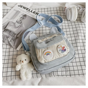 Detail of light blue nylon bag with cute bear ears, badges and plush bear charm