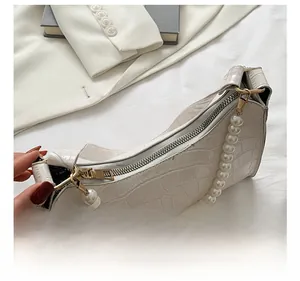 Detail of white crocodile pattern hobo bag with pearl strap and metal zipper closure