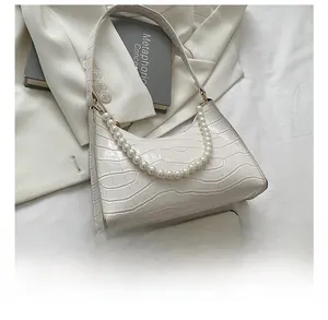 Size comparison of white croc-effect hobo bag with pearl strap next to a mobile phone