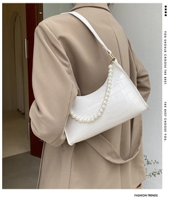 Detailed shot of white faux-crocodile underarm bag with elegant large pearl chain strap