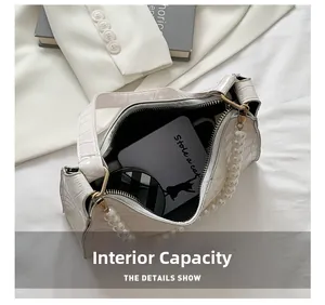 Internal capacity of off-white dumpling bag with pearl strap and crocodile texture