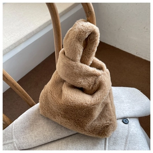 Minimalist camel faux fur handbag with knotted handle on top of a winter wool coat