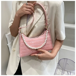 Detailed close-up of pink crocodile texture underarm bag with white pearl chain strap