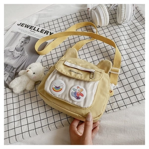 Detail of yellow nylon crossbody bag featuring cute ear decor and transparent badge pocket