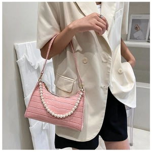 Detail of pink faux crocodile leather shoulder bag with elegant pearl chain accessory