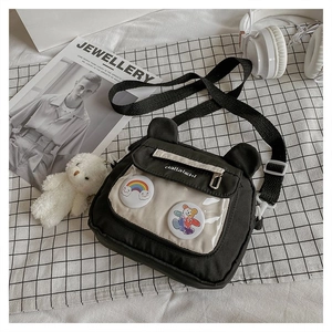 Detail of black nylon shoulder bag with bear ears, transparent PVC pocket and pins