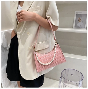 Close-up of pink crocodile texture leather and elegant large pearl handle on hand bag