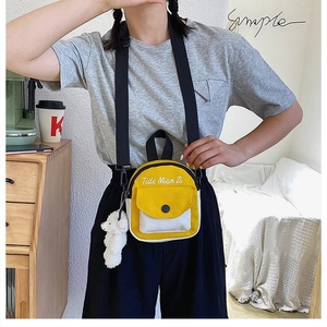 Close-up of yellow and white canvas mini crossbody bag with plush bear accessory
