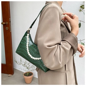 Detail of green crocodile pattern leather underarm bag with large pearl strap decoration