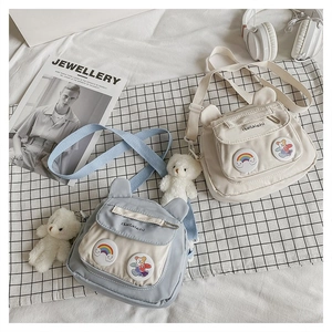 Detail of cute bear-eared nylon shoulder bags with rainbow patches and plush charms