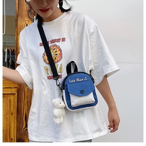 Blue and white canvas crossbody bag shown on model with a cute white plush bear charm