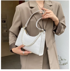 Detailed view of white faux leather crescent bag with crocodile texture and pearl strap