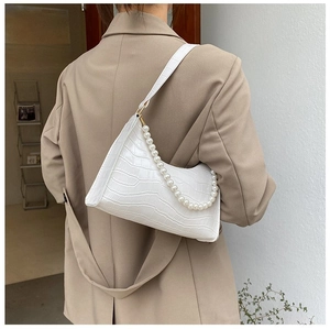 Detail of white crocodile pattern shoulder bag with elegant pearl chain and leather strap