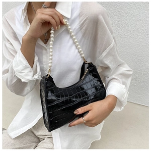 Model showing a black crocodile pattern underarm bag with pearl chain and glossy finish