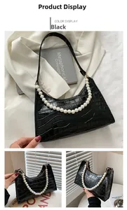 Detail of black faux crocodile skin underarm bag with decorative large pearl chain strap